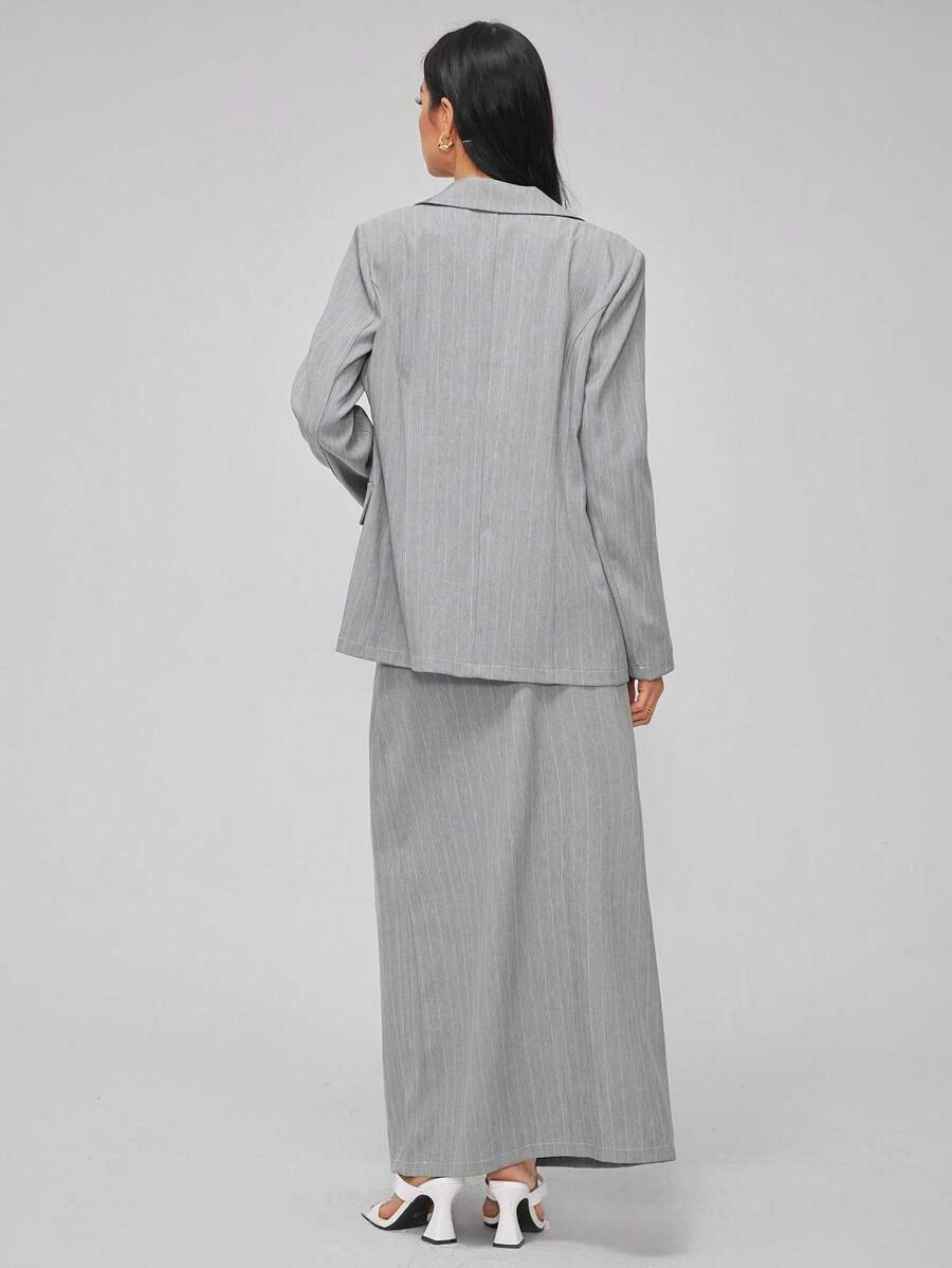 Cotiful pinstripe blazer worn open with a white crop top and long pinstripe skirt